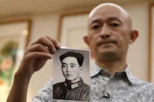 Zhang Hai holds up a photo of his father taken in his youth during an interview in Shenzhen in southern China's Guangdong province on Friday, Oct. 16, 2020. Zhang is demanding to meet a visiting World Health Organization expert team, saying it should speak with affected families who allege they are being muffled by the Chinese government.(AP Photo/Ng Han Guan)